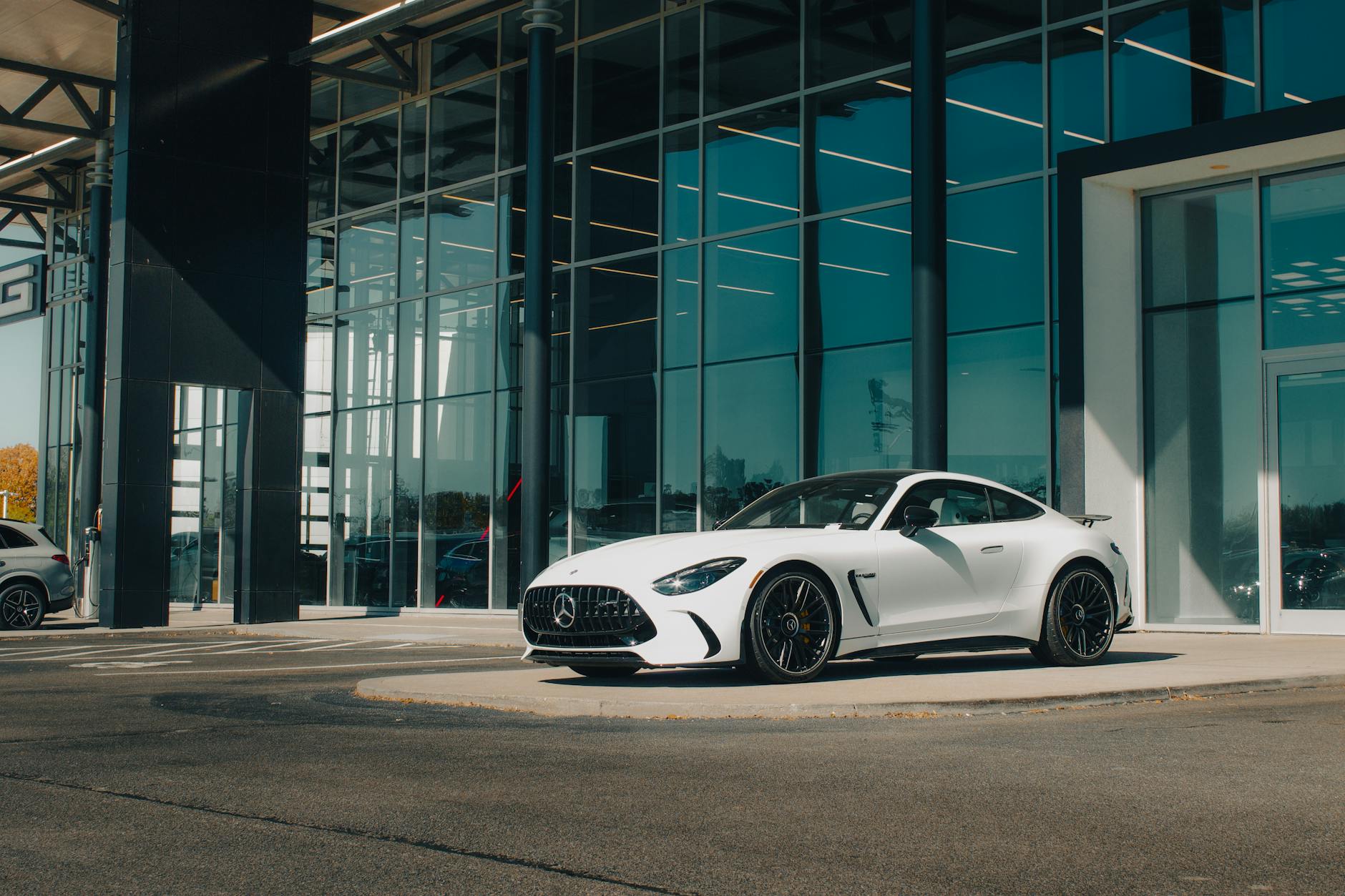Białe Mercedes-Benz AMG przed przeszklonym salonem premium