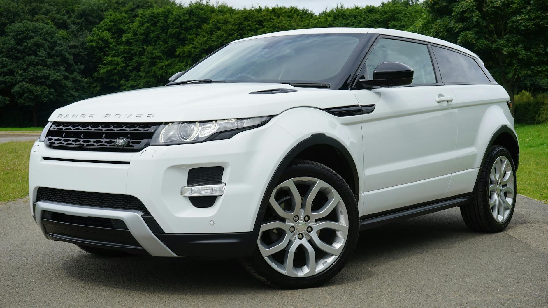 Biały Range Rover zaparkowany na wiejskiej drodze w zielonym otoczeniu