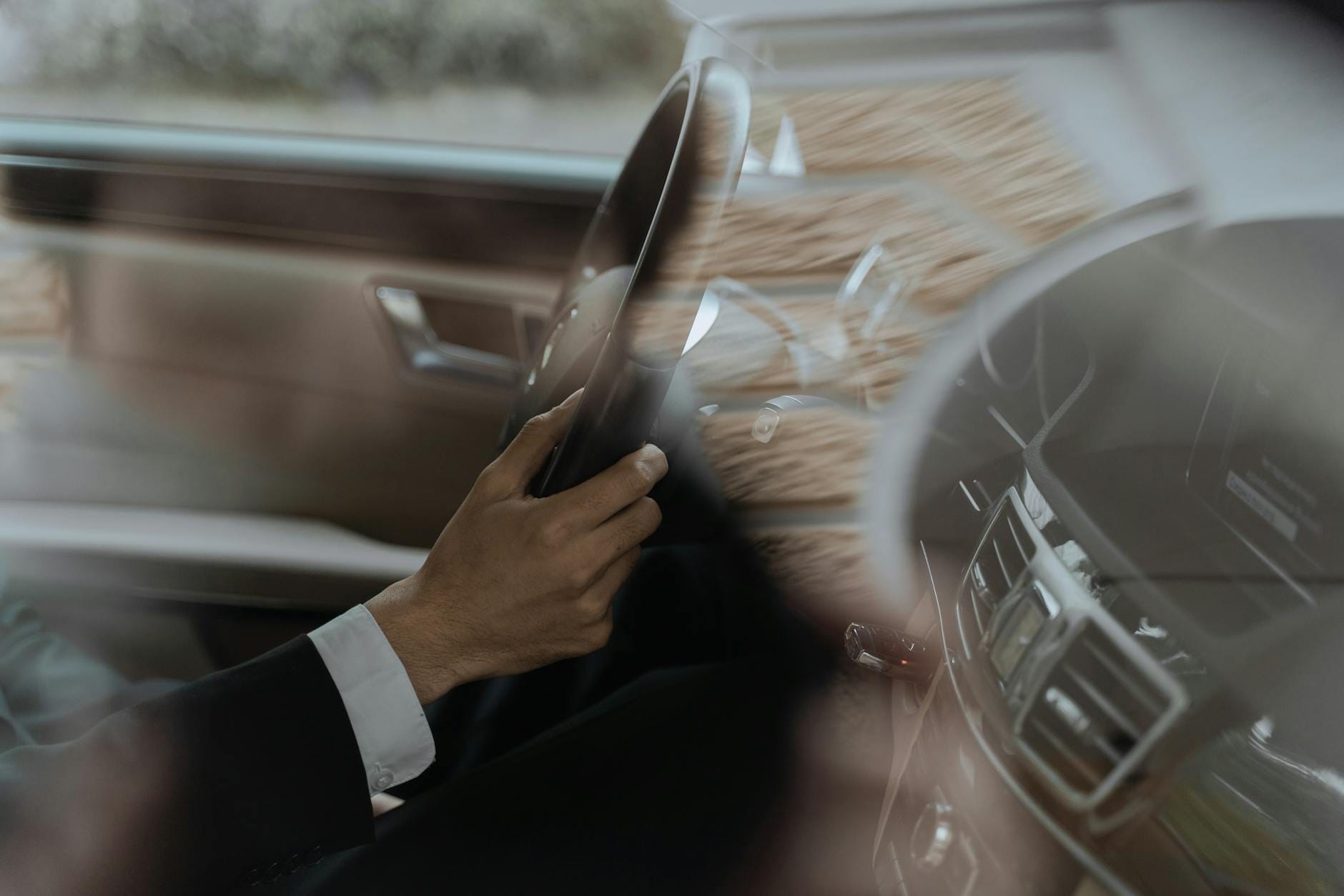 Czy warto dopłacać do pakietów stylistycznych w premium? Dłoń kierowcy na kierownicy luksusowego auta w eleganckim wnętrzu