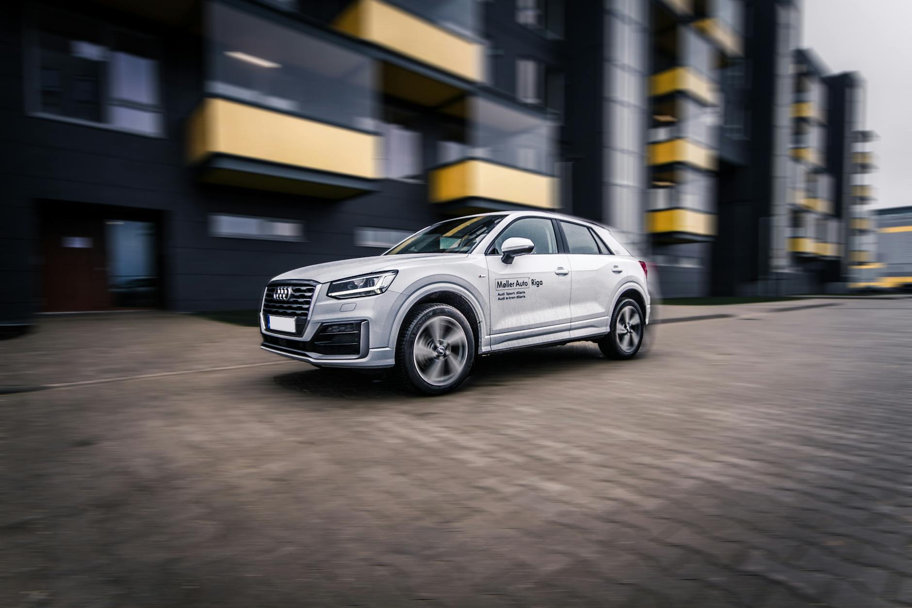 Jadące ulicą nowoczesne Audi SUV na tle miejskich wieżowców