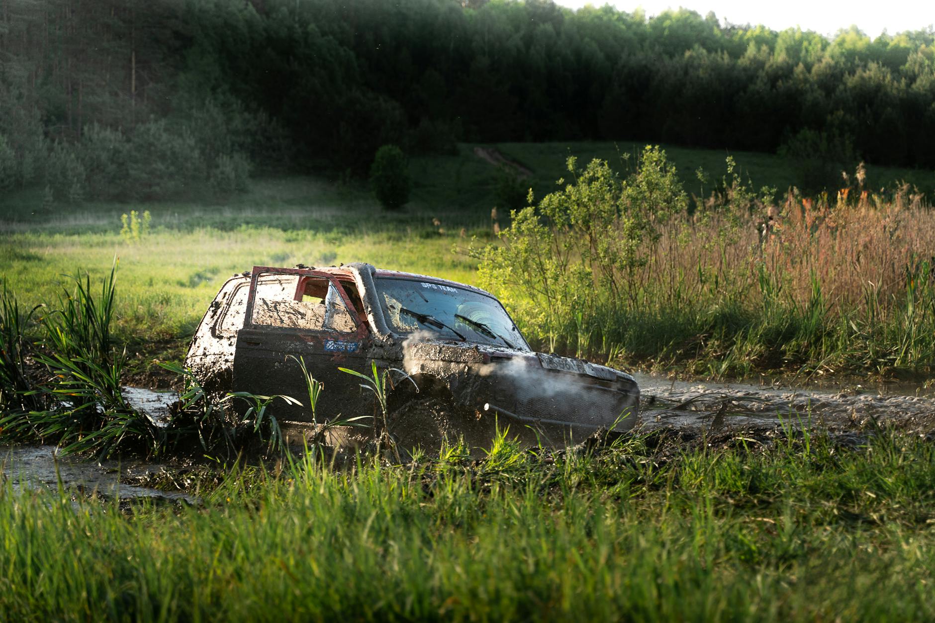 SUV terenowy jadący po błotnistej drodze wśród traw w ciągu dnia