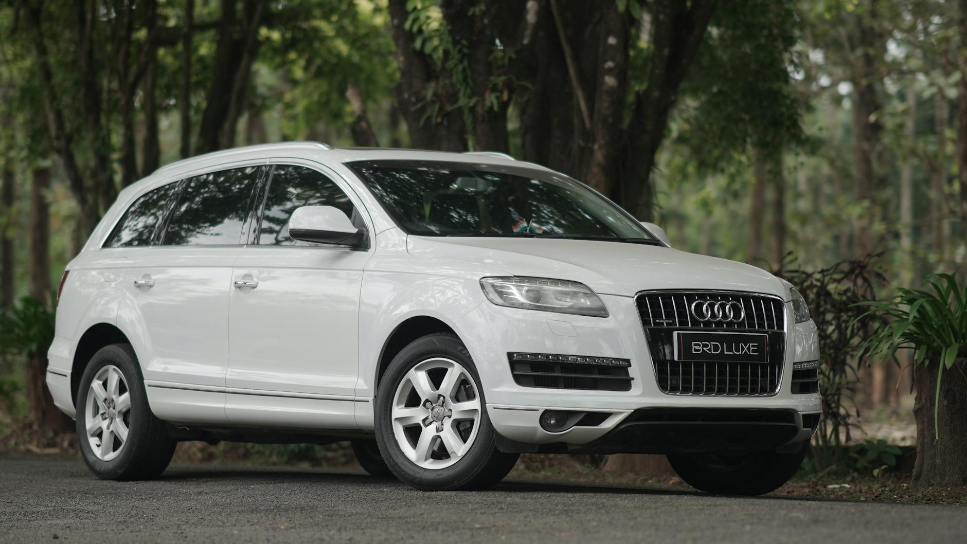 Mit o „niemieckiej niezawodności” w klasie premium: co pokazują statystyki? Białe Audi SUV zaparkowane na leśnej drodze otoczone zielenią