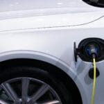 Luksusowe hybrydy plug in: czy to jeszcze ma sens w 2026? Biały samochód elektryczny premium podłączony do ładowania zbliżenie