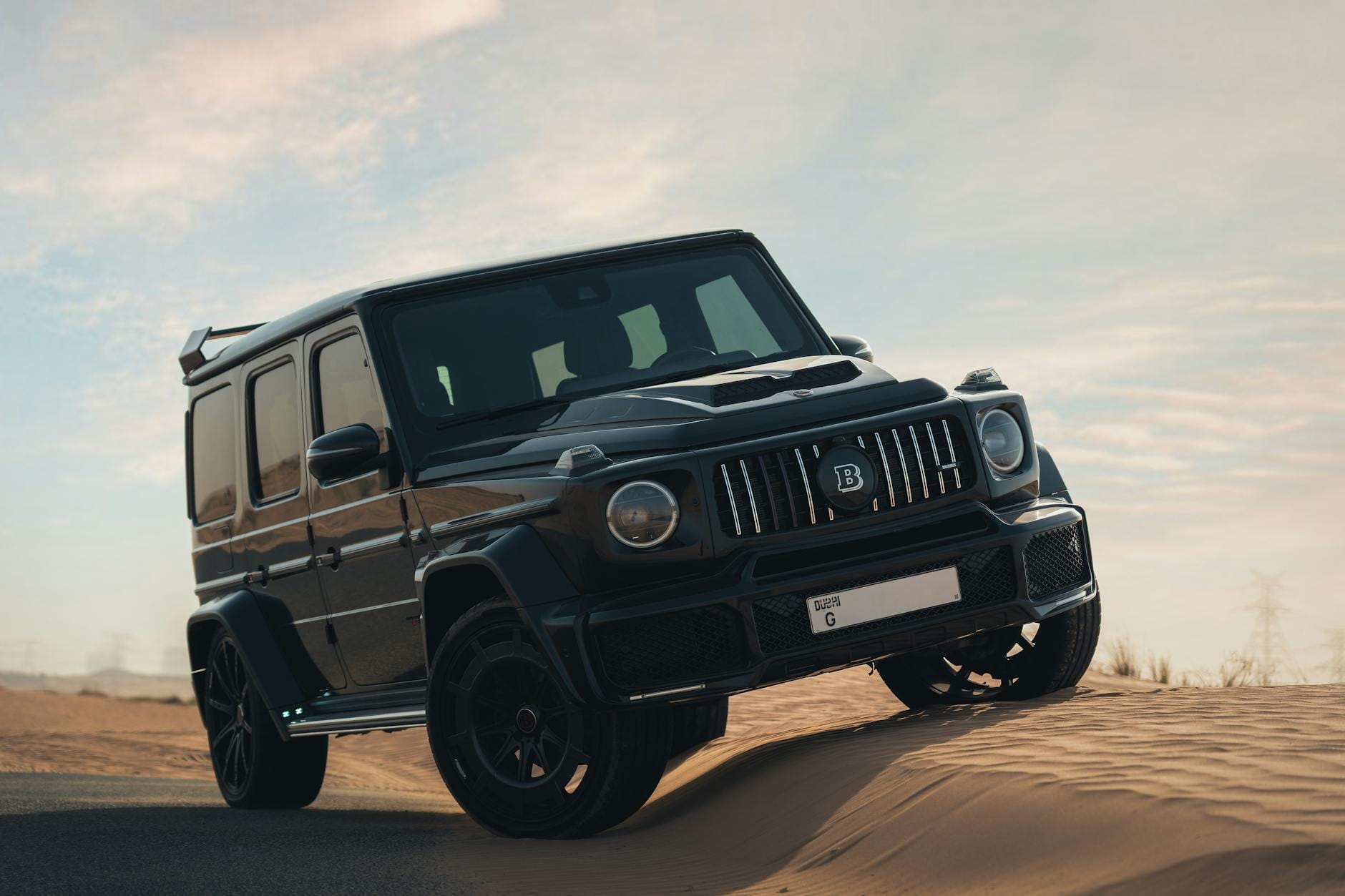 Czarny Range Rover Sport jedzie po pustynnych wydmach o zmierzchu