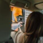 Jak kupić używany samochód elektryczny premium i nie wpaść na minę? Kierowca auta elektrycznego płaci zbliżeniowo w fast food drive-thru