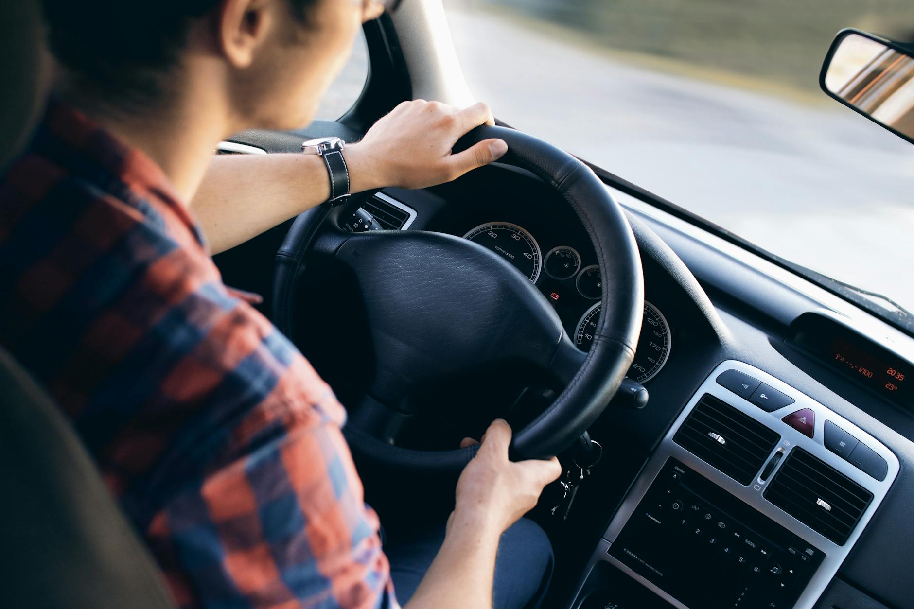 Mężczyzna prowadzi nowoczesne auto, zbliżenie na kokpit i kierownicę