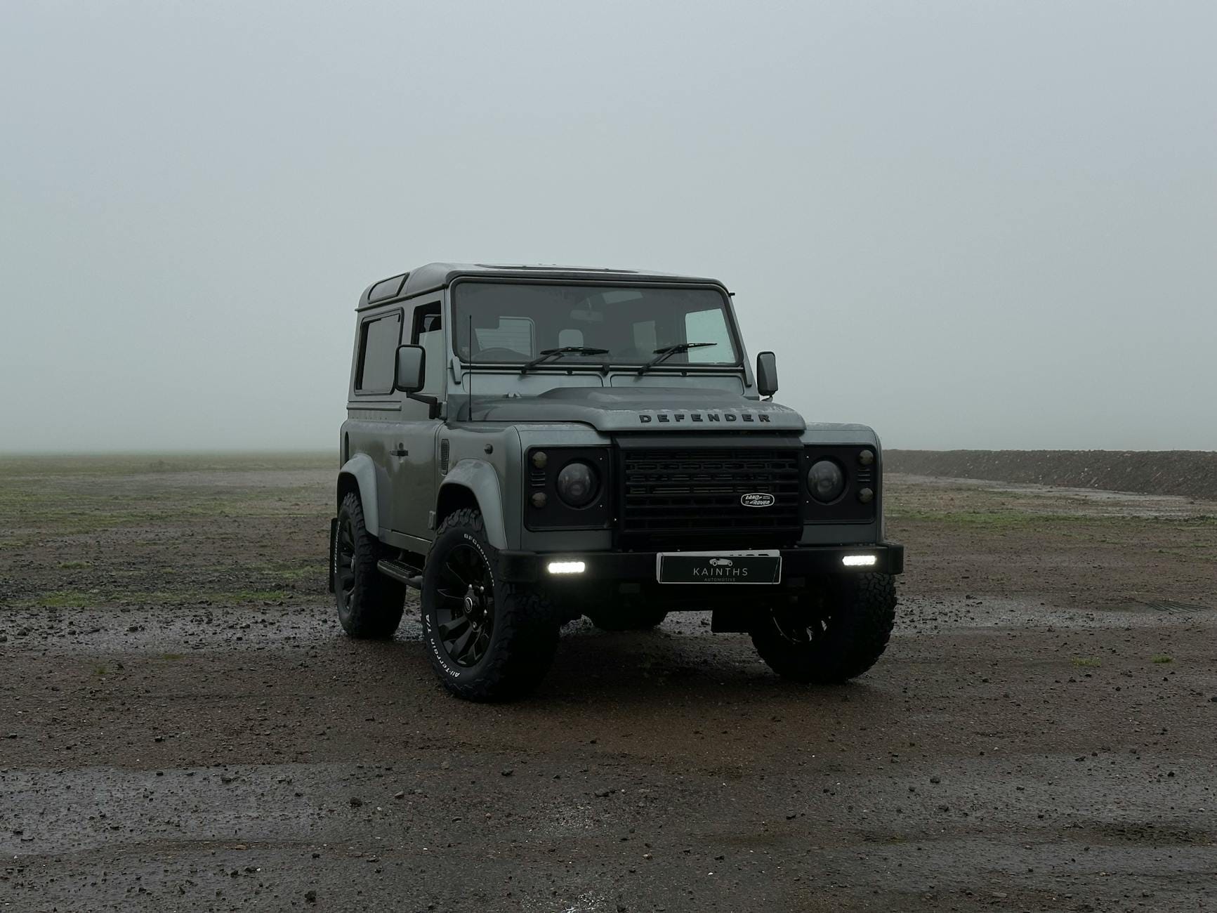 Szary Land Rover Defender zaparkowany w deszczu na ulicy w Londynie