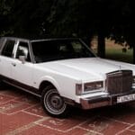 Klasyczny Lincoln Town Car zaparkowany na brukowanym podjeździe w zieleni