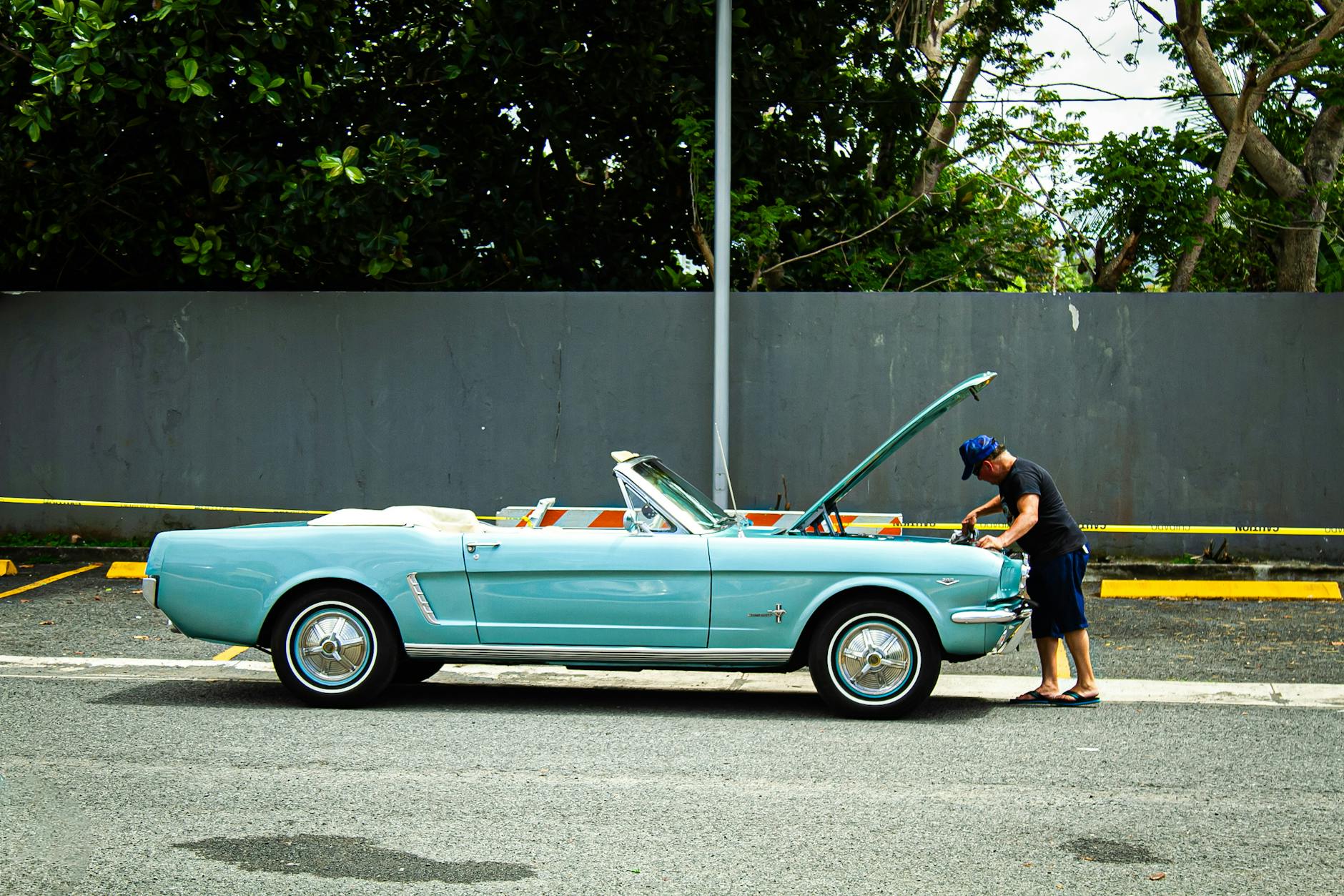 Mężczyzna ogląda niebieskie cabrio w stylu retro zaparkowane przy ulicy