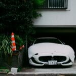 Biały Maserati przykryty pokrowcem na podjeździe obok pachołka