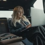 Bizneswoman z laptopem na tylnej kanapie luksusowego auta