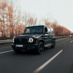 Czarny luksusowy SUV jedzie autostradą w jesiennej scenerii