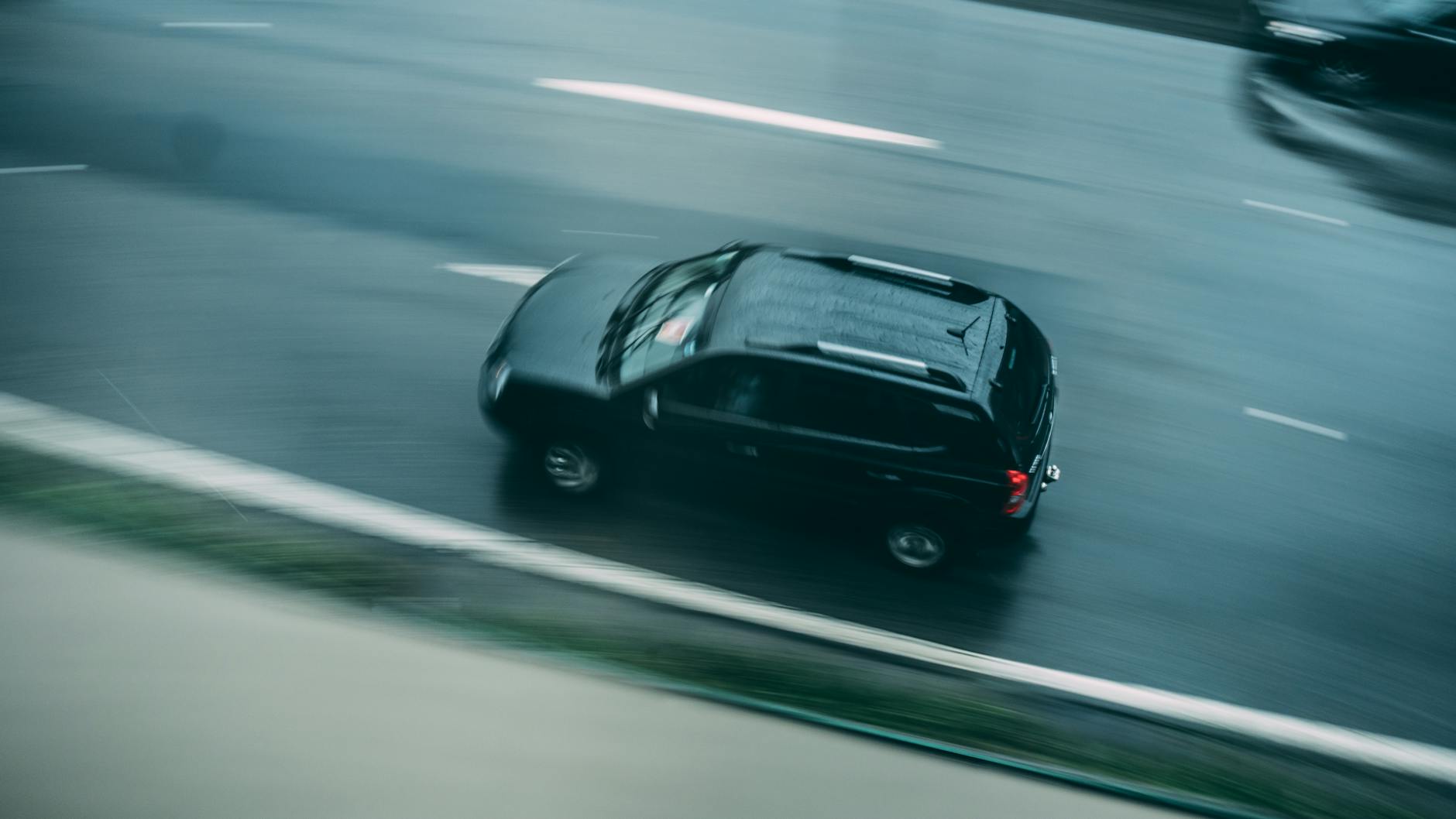 Czarny SUV przyspiesza na mokrej autostradzie podczas deszczu Czarny SUV przyspiesza na mokrej autostradzie podczas deszczu