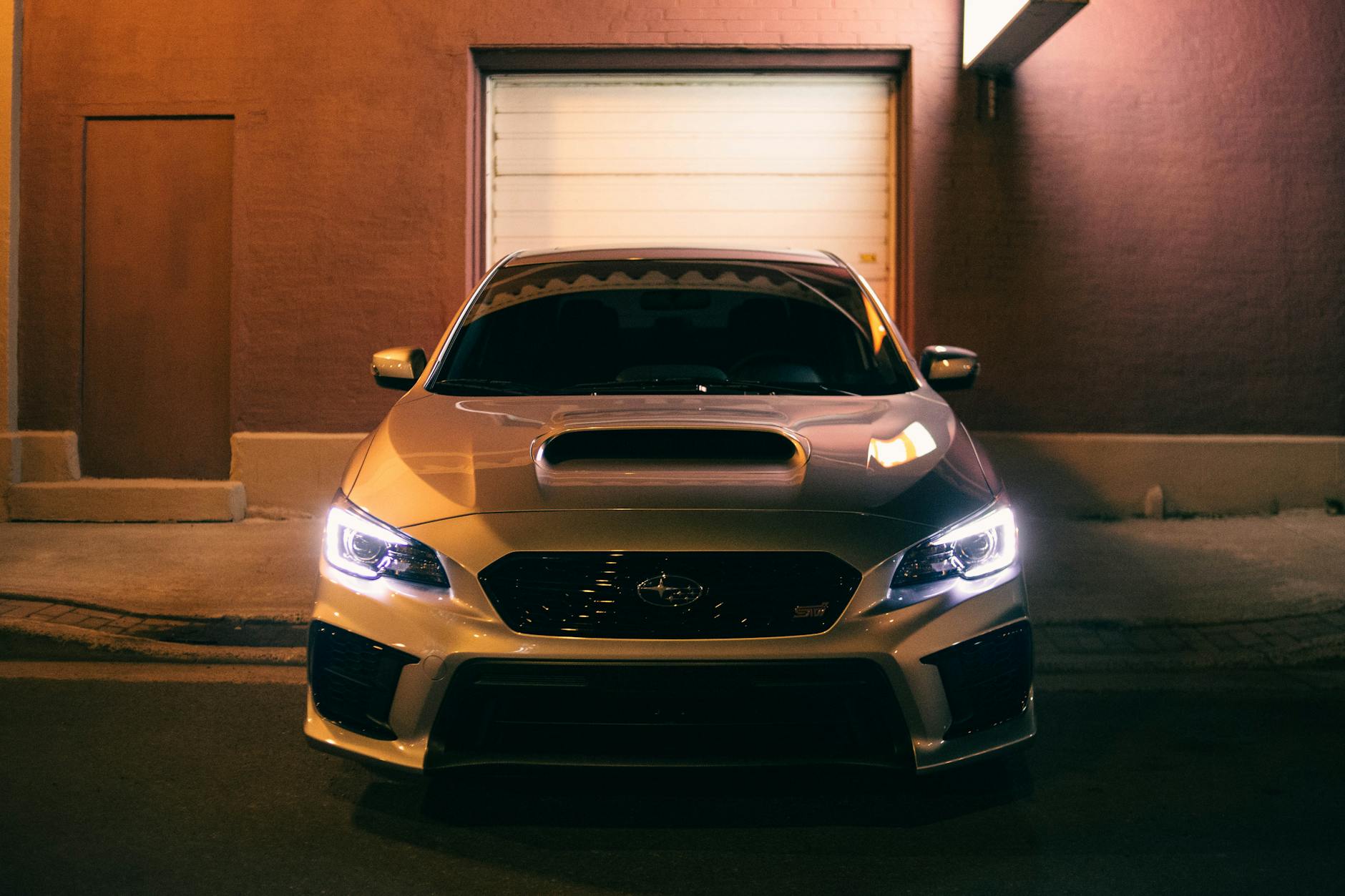 Sedan w mieście nocą z włączonymi reflektorami LED