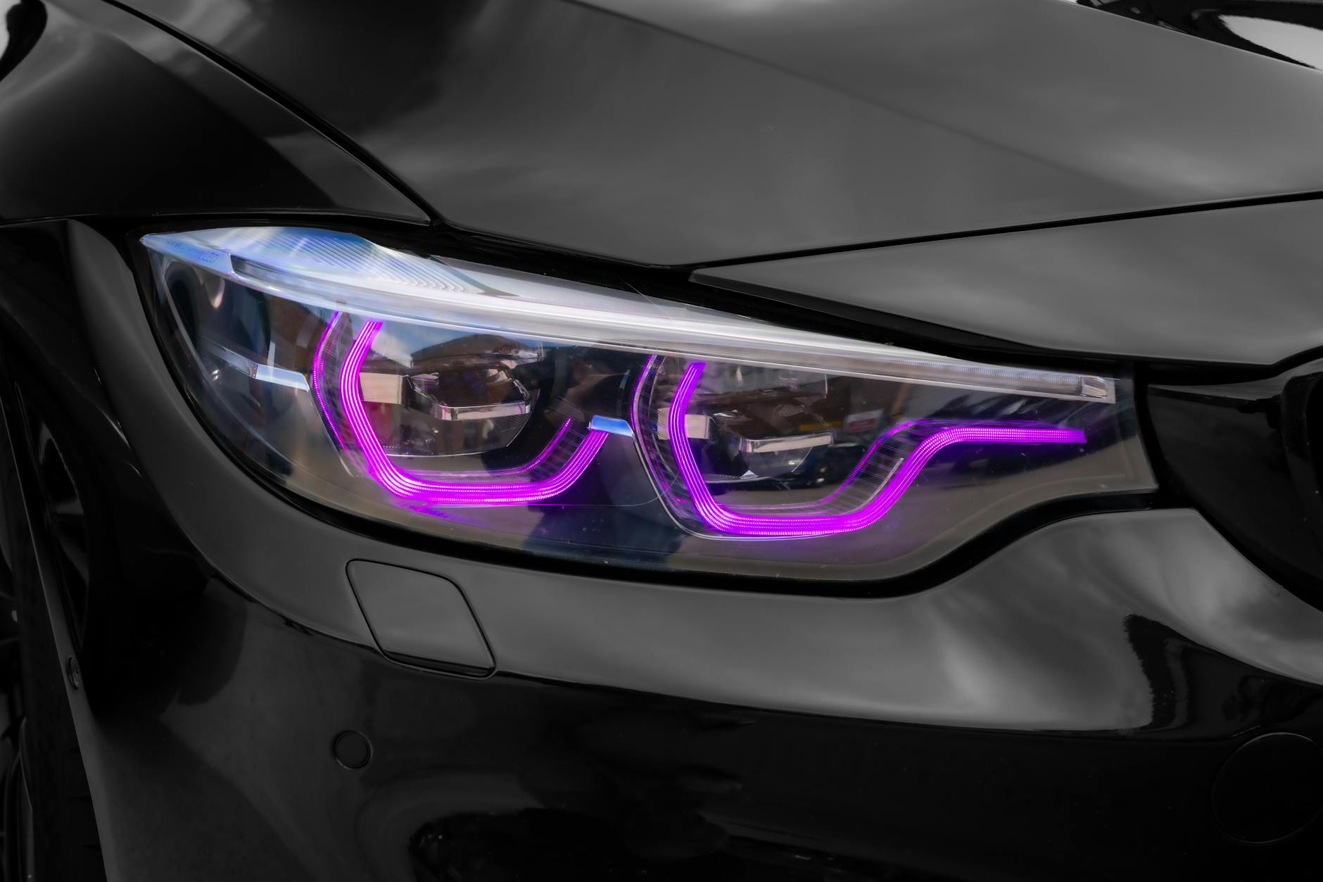Zbliżenie reflektora LED z fioletową poświatą w czarnym nadwoziu auta