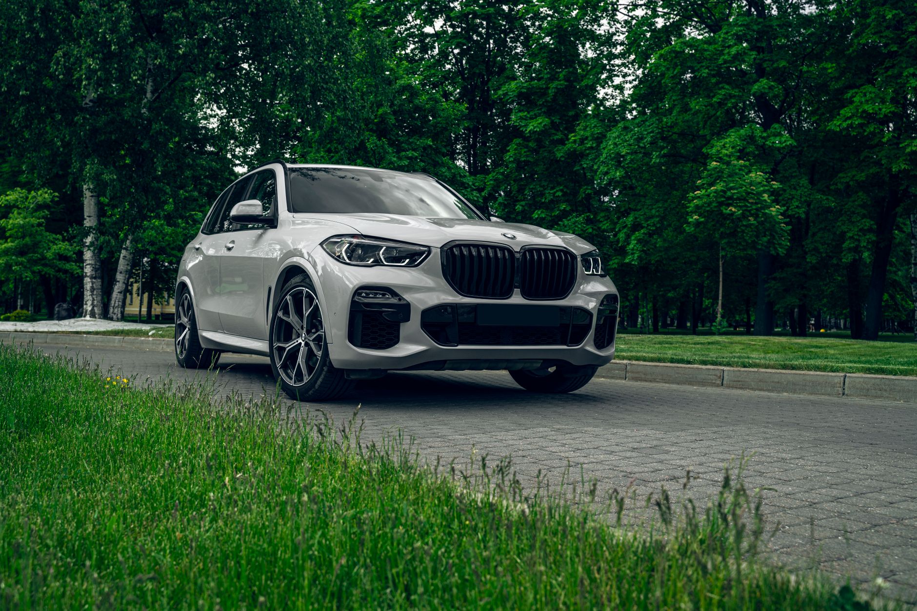 Leasing czy wynajem długoterminowy SUV-a premium: co wychodzi taniej w 2026 roku? Białe BMW X5 SUV zaparkowane na malowniczej, zielonej drodze