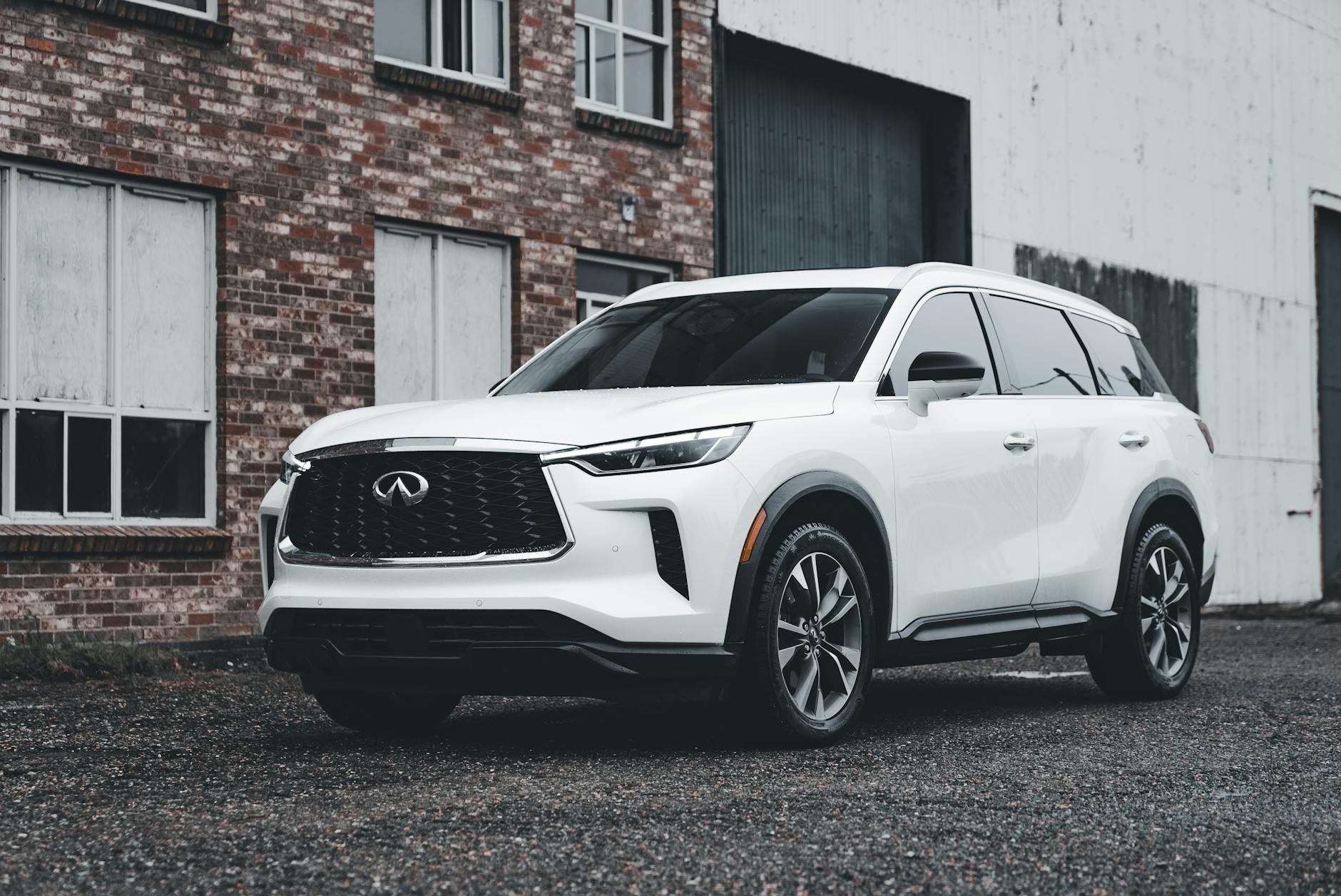 Biały luksusowy SUV zaparkowany przed ceglaną fasadą budynku Biały luksusowy SUV zaparkowany przed ceglaną fasadą budynku