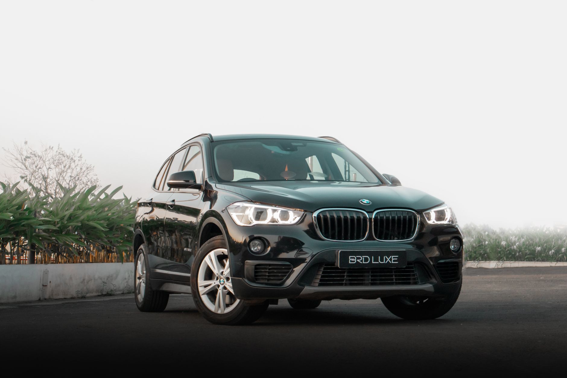 Czarny SUV premium z włączonymi światłami na tle zieleni