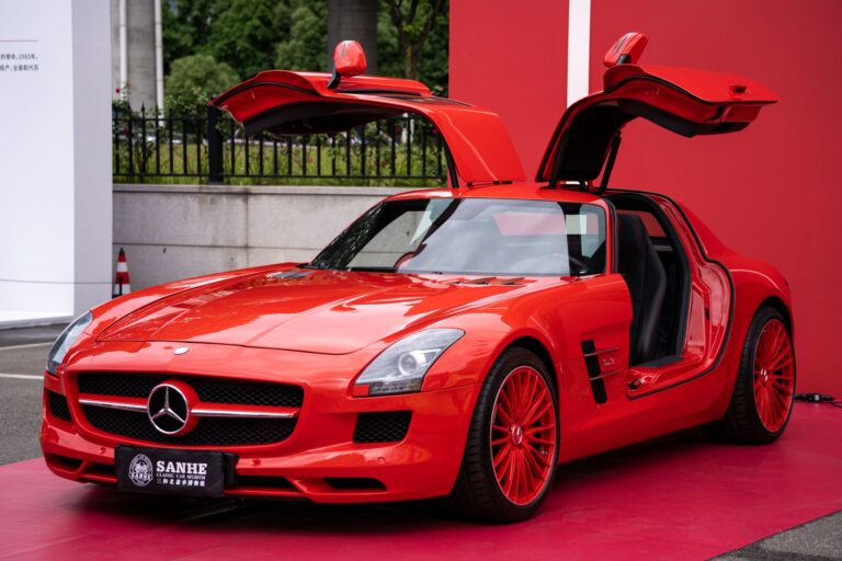 Czerwony Mercedes-Benz SLS AMG z otwartymi drzwiami gullwing na czerwonym dywani
