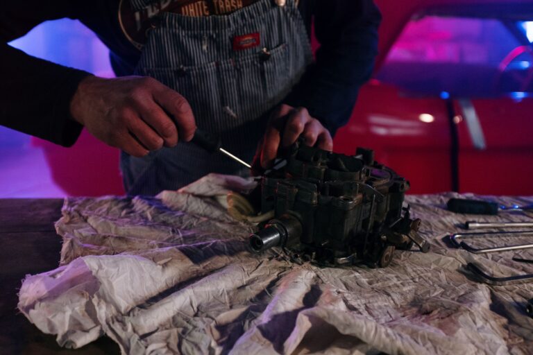 Mechanik naprawiający część zabytkowego auta w garażu z neonami