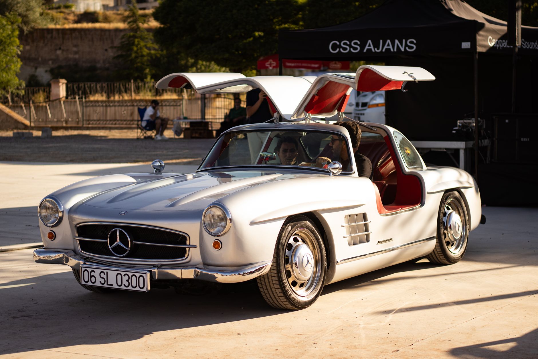 Srebrny Mercedes-Benz 300 SL z otwartymi drzwiami skrzydłowymi w słońcu
